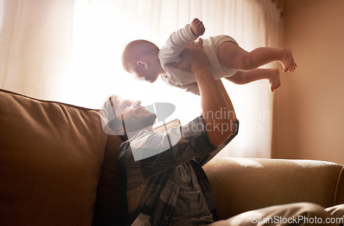 Image of Dad, funny and lifting baby on sofa in home living room, playing or bonding together. Laughing, care and father holding infant, newborn or child on couch in lounge, having fun and enjoying time.