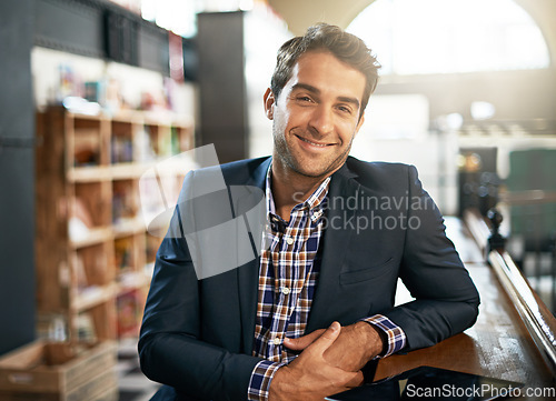 Image of Portrait, relax and happy with a man in a coffee shop, sitting at a bar counter as a customer during the day. Cafe, smile and fashion with a handsome young male consumer in a trendy restaurant