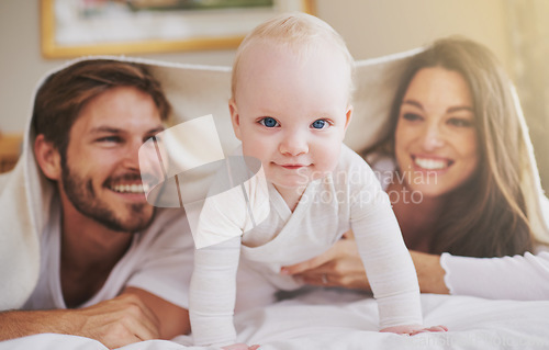 Image of Baby, mother and father playing with blanket in bedroom for love, care and quality time together. Portrait of cute newborn child with parents, happy family and relax with bedding over heads at home