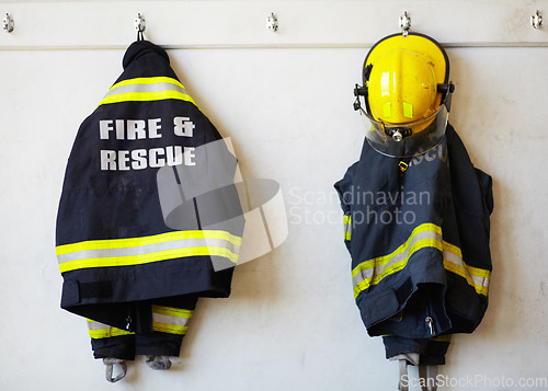 Image of Firefighter, uniform and clothing hanging on wall rack at station for fire fighting protection. Fireman gear, rescue jacket and helmet with reflector for emergency services, equipment or department