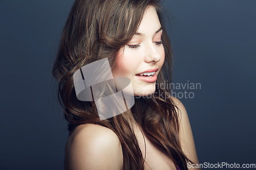 Image of Beauty, cosmetic and young woman in a studio with a natural, face and makeup routine. Self care, beautiful and young female model with cosmetics, dermatology or skincare treatment by blue background.