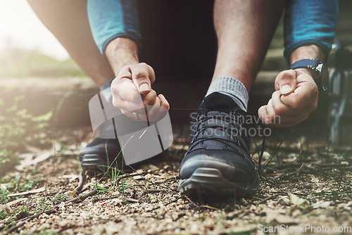 Image of Tying laces, hiking and hands in nature to start walking, adventure or trekking for exercise. Shoes, sports and feet of a man getting ready for cardio, training or a walk for fitness in a park