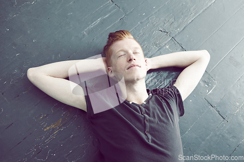 Image of Relax, overhead and a man lying on the floor, hands behind head to sleep, rest or dream of peace. Quiet, sleeping and lifestyle with a young ginger male person relaxing on the ground from above