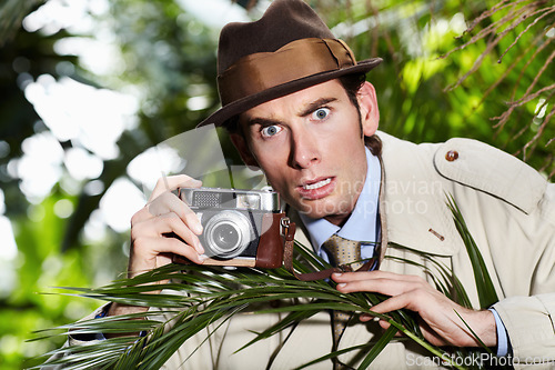 Image of Retro spy man, camera and jungle for investigation, inspection or journalist with shock at job. Private investigator, secret photographer and retro paparazzi in trees, bush or leaves for surveillance