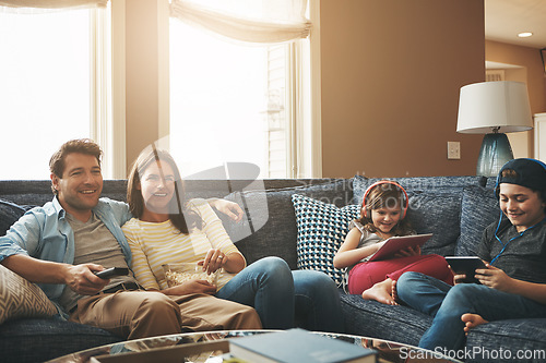 Image of Technology, happy family together and in living room of their home with lens flare. Connectivity, networking or streaming and parents watching tv with children on tablet or smartphone with headphones