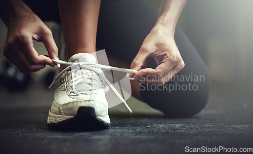 Image of Woman tie shoe laces, hands and fitness with athlete in gym and sports with training for health. Closeup of runner sneakers, start workout in exercise studio with healthy and active female person