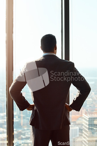 Image of Thinking, building window and a business man with ideas, vision or plan for cityscape. Professional male entrepreneur with hands on hips for dream, growth and corporate development from behind