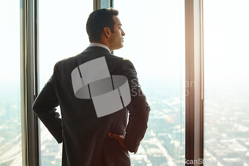 Image of Business man, office window and thinking of ideas, plan or vision with cityscape. Professional male executive with hands on hips for opportunity, dream and future corporate development from behind