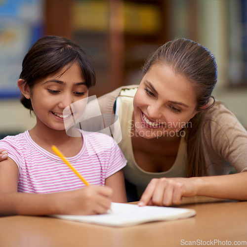 Image of School, education or learning with a student and teacher in a classroom together for writing or child development. Study, scholarship and teaching with a woman educator helping a girl child in class