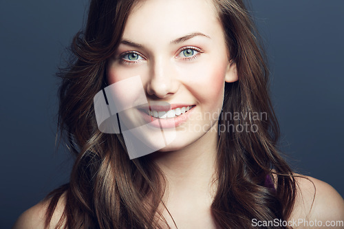 Image of Cosmetic, beauty and portrait of a woman in a studio with a natural, facial and skincare routine. Happy, smile and face of a young female model with makeup or dermatology treatment by blue background