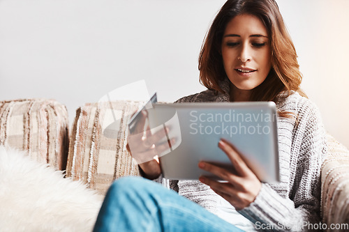 Image of Internet, tablet and credit card with an ecommerce woman on a sofa in the living room of her home. Online shopping, finance and fintech payment with a young female online customer in her house