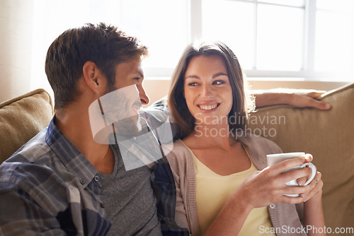 Image of Coffee, love and couple smiling at each other or on a couch in the living room or bonding and conversation. Man, woman and communicating or affectionate with hot beverages or happy partners at home