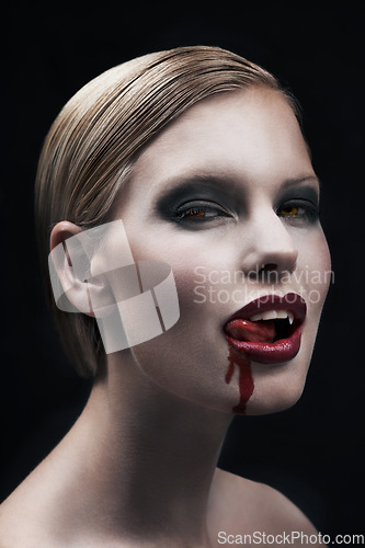 Image of Portrait, blood and a woman vampire in studio on a dark background for halloween or cosplay. Fantasy, horror or scary with an attractive young female monster posing as an evil and feminine creature