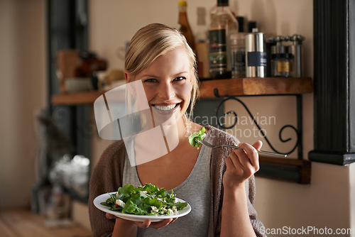 Image of Young, woman and eating a salad in kitchen with a smile with wellness and lettuce for cooking. Girl, healthy and vegetables on plate for nutrition or diet in house with hungry person in the usa.