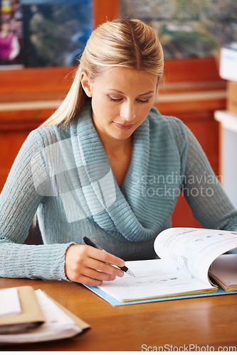 Image of Woman, education career and teacher writing or marking test paper with a pen and focus at a desk in a classroom. Professional female person working at academic school with paperwork for exam results