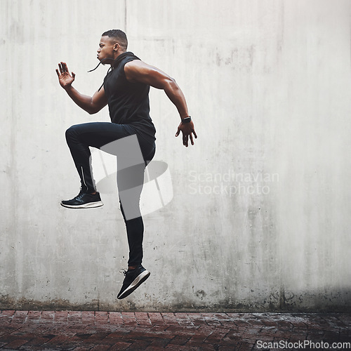 Image of Jump, fitness and black man running, speed and energy for cardio training, workout and sports wellness or body health. Athlete, runner or person exercise on concrete wall, action run or moving in air