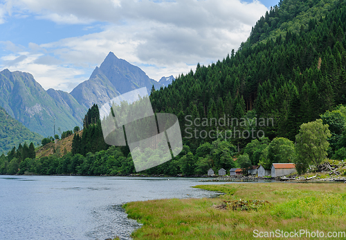 Image of boathouse by the sea and mountains in the background