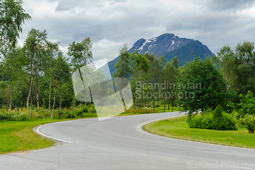 Image of road bend between trees and mountains