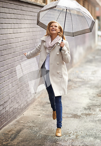 Image of Rain umbrella, city street and woman jump with happiness on a sidewalk from winter weather. Happy female person, raining and travel on urban road outdoor in Cape Town on holiday with freedom and joy