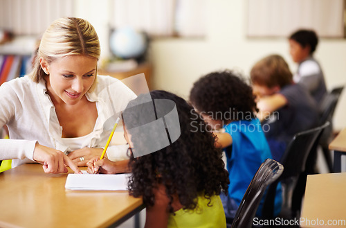 Image of School, education or learning with a teacher and student in a classroom during a lesson for child development. Study, kids or writing with a woman educator helping a girl pupil while sitting in class