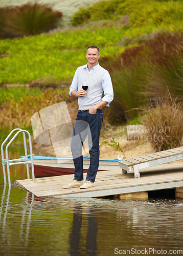 Image of Portrait, lake and mature man with red wine, vacation and smile on a weekend break, getaway and happiness. Face, male person and happy guy on a summer holiday, alcohol and outdoor to relax and chill