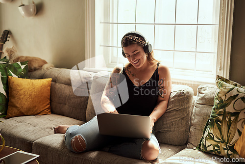 Image of Computer, headphones and woman on sofa and music, happy work from home for mental health in apartment. Young person relax on couch and listening to audio technology, electronics and working on laptop