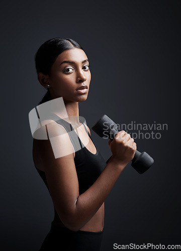 Image of Portrait, serious and woman with dumbbell for exercise in studio isolated on black background. Strong, bodybuilder and female athlete with weight for muscle, strength or fitness, workout or training.