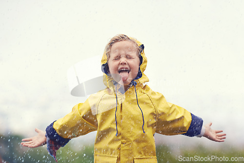 Image of Winter, raincoat and a girl playing in the rain outdoor alone, having fun during the cold season. Kids, water or wet with an adorable little female child standing arms outstretched outside in the day