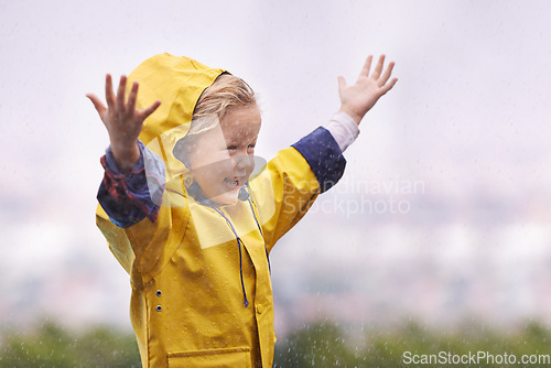 Image of Winter, raincoat and a girl having fun in the water outdoor alone, playing during the cold season. Kids, rain or wet with an adorable little female child standing arms outstretched outside in the day