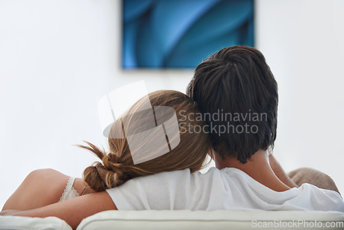 Image of Back, relax and a couple watching tv on the sofa with affection, comfort and content at home. Calm, love and a man and woman sitting on the living room couch for a movie, film or show on television