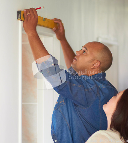 Image of Spirit meter, man contractor and measure for maintenance, home improvement with wife. Construction, couple and male person with pencil drawing on a wall for level measuring of handyman and line