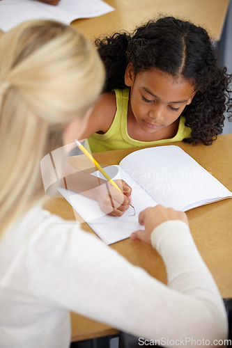 Image of Teacher help child, education and writing in notebook with pencil, teaching and learning for growth and development. People in classroom to learn, academic study with young girl and woman at school