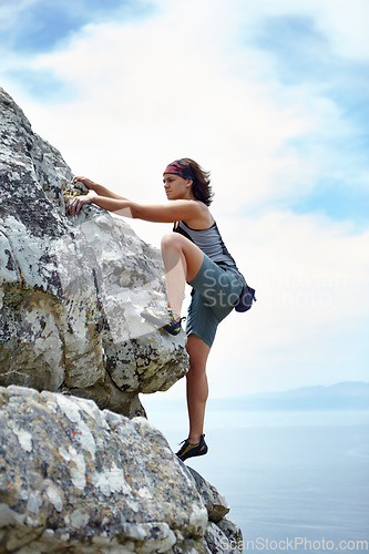 Image of Woman, mountains and rock climbing on blue sky for sports, outdoor adventure and fitness challenge of strong athlete. Exercise, climber and hiking stone cliff with fearless courage on mockup space