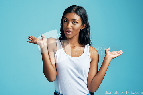 Image of Options, choice gesture and portrait of woman in studio with shock, surprise or thinking face. Decision, idea and Indian female model with comparison or shrug hand sign by blue background with mockup