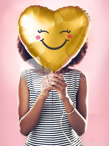 Image of Love, smile and a woman with a heart balloon isolated on a pink background in a studio. Happy, cute and a girl holding a present or gift for valentines day or a birthday for care and happiness
