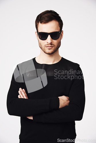 Image of Sunglasses, fashion and man in studio with crossed arms for confidence, pride and stylish clothing. Portrait, style and serious male person with funky, cool and trendy eyewear on white background