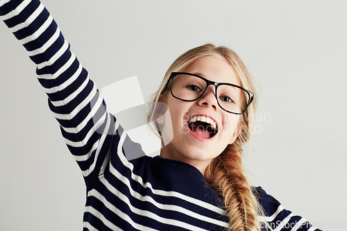 Image of Happy, excited and portrait of young girl with happiness to celebrate isolated in a white studio background. Glasses, vision and female kid smile with freedom in a strip t-shirt for child fashion