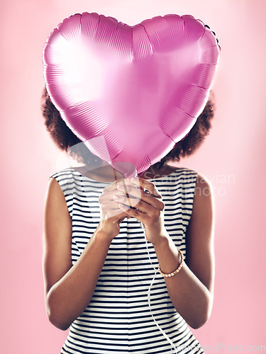 Image of Woman cover face with heart balloon in studio, pink background and celebrate surprise birthday party. Female model hide with helium, gift and present for love, valentines day and secret celebration