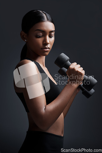 Image of Sports, serious and woman with dumbbell for workout in studio isolated on a black background. Strong, bodybuilder and Indian female athlete weightlifting for muscle, training and fitness exercise.