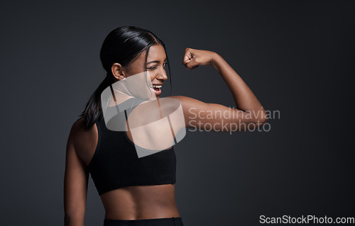 Image of Wink, happy and woman flexing muscle in studio isolated on a black background mockup. Strong flex, funny and Indian female athlete with bicep, arm strength or bodybuilder back, fitness or workout.