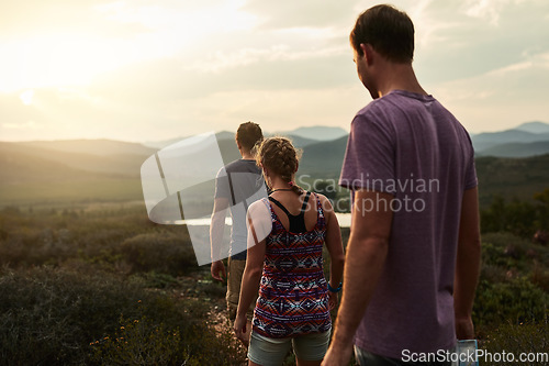 Image of Friends, people hiking and trekking in nature with fitness, bond in countryside with travel together and freedom. Exercise, adventure with men and woman walking through meadow or field with back view