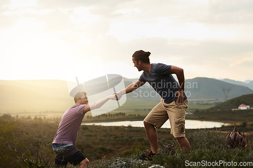 Image of Hiker helping friend while hiking, fitness and men outdoor trekking in nature or countryside for exercise and travel. Young people hike together, support and adventure with friends, bond and workout