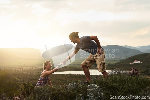 Image of Man helping woman while hiking, fitness and couple outdoor trekking in nature or countryside for exercise and travel. Young people hike together, support and adventure with date, bonding and workout