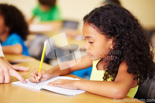 Image of Child, writing and hand of teacher helping student at school for education, learning or development. Woman teaching girl with notebook, pencil and knowledge in a classroom with support at desk