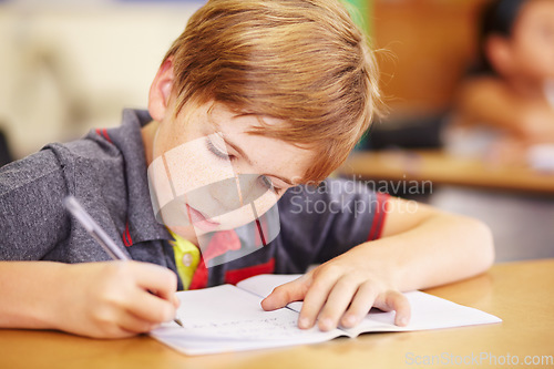 Image of Education, student and boy writing, focus and learning with creativity, book and reading. Male person, child and kid in school, classroom and knowledge with exam, future and test for development