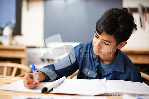 Image of Education, writing and boy child in a classroom for studying, exam or assignment, focused and serious. Learning, book and male student with notes in an educational lesson, creative and thinking