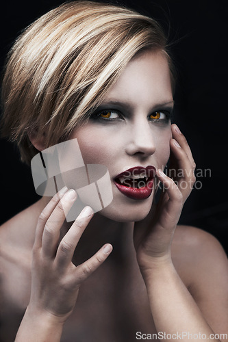 Image of Portrait, hands and a woman vampire in studio on a dark background for halloween or cosplay. Fantasy, horror or fangs with an attractive young female monster posing as an evil and surreal creature