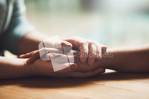 Image of Love, empathy and support with people holding hands in comfort, care or understanding on a wooden table of a home. Prayer, faith or depression with friends closeup for hep, hope or peace for healing