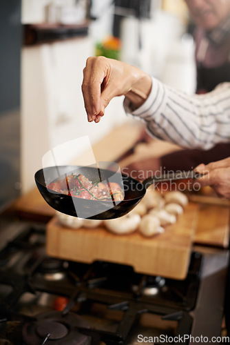 Image of Hand, cooking and seasoning with a chef in the kitchen for meal preparation in a home for dinner. Healthy, diet and nutrition with food in a pan for wellness, hunger or satisfaction in a house