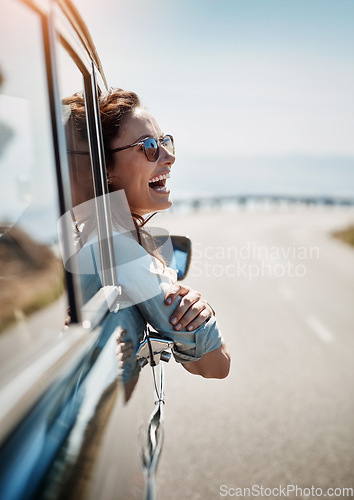 Image of Happy, freedom and road trip with a woman in a car, looking at the view from the window while on the open road. Smile, travel and fun with a young female traveler on a journey during her vacation